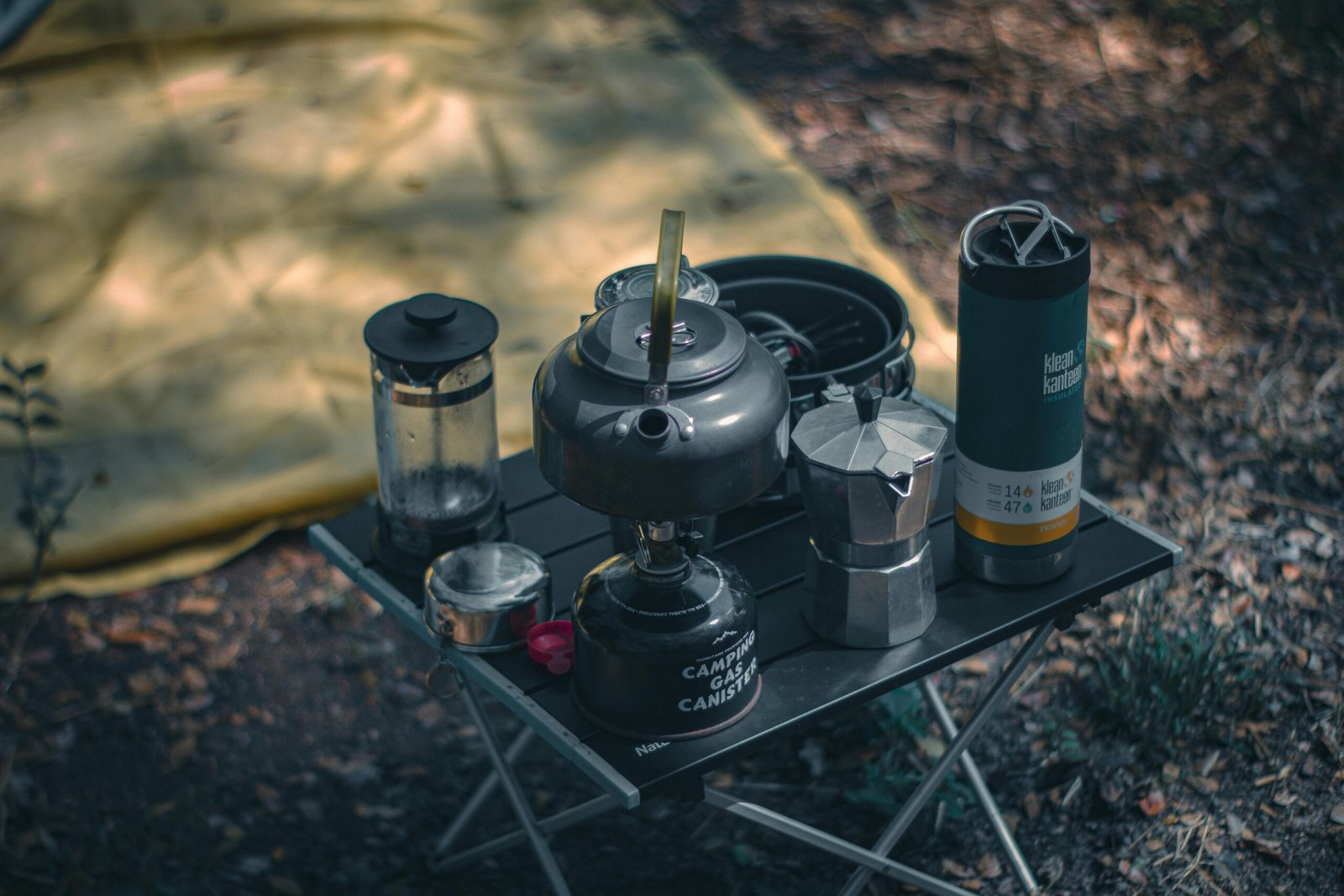 A cozy camping setup featuring coffee-making equipment and a tent outdoors.